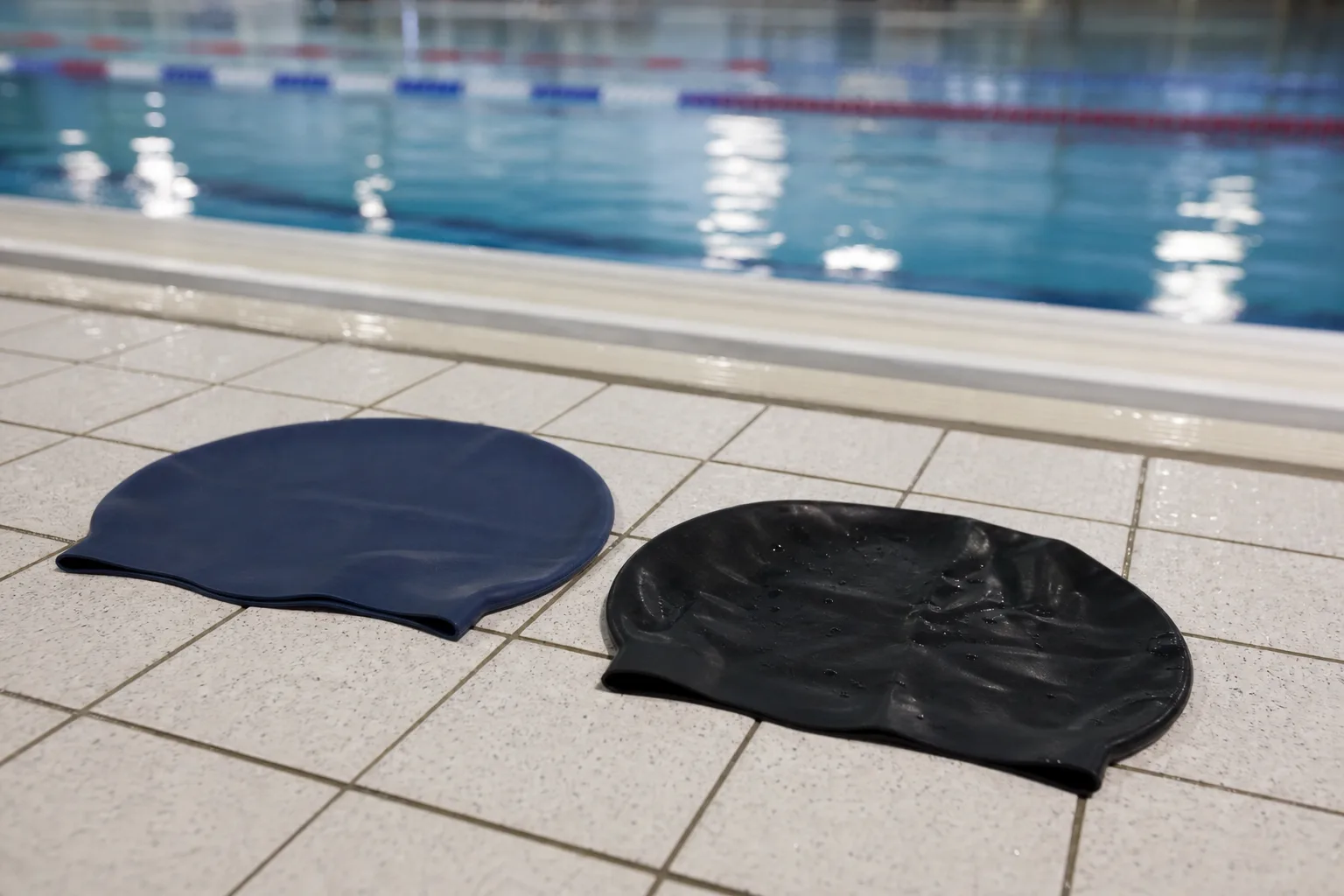 Silikon- och latexbadmössa jämförs sida vid sida på bassängkant